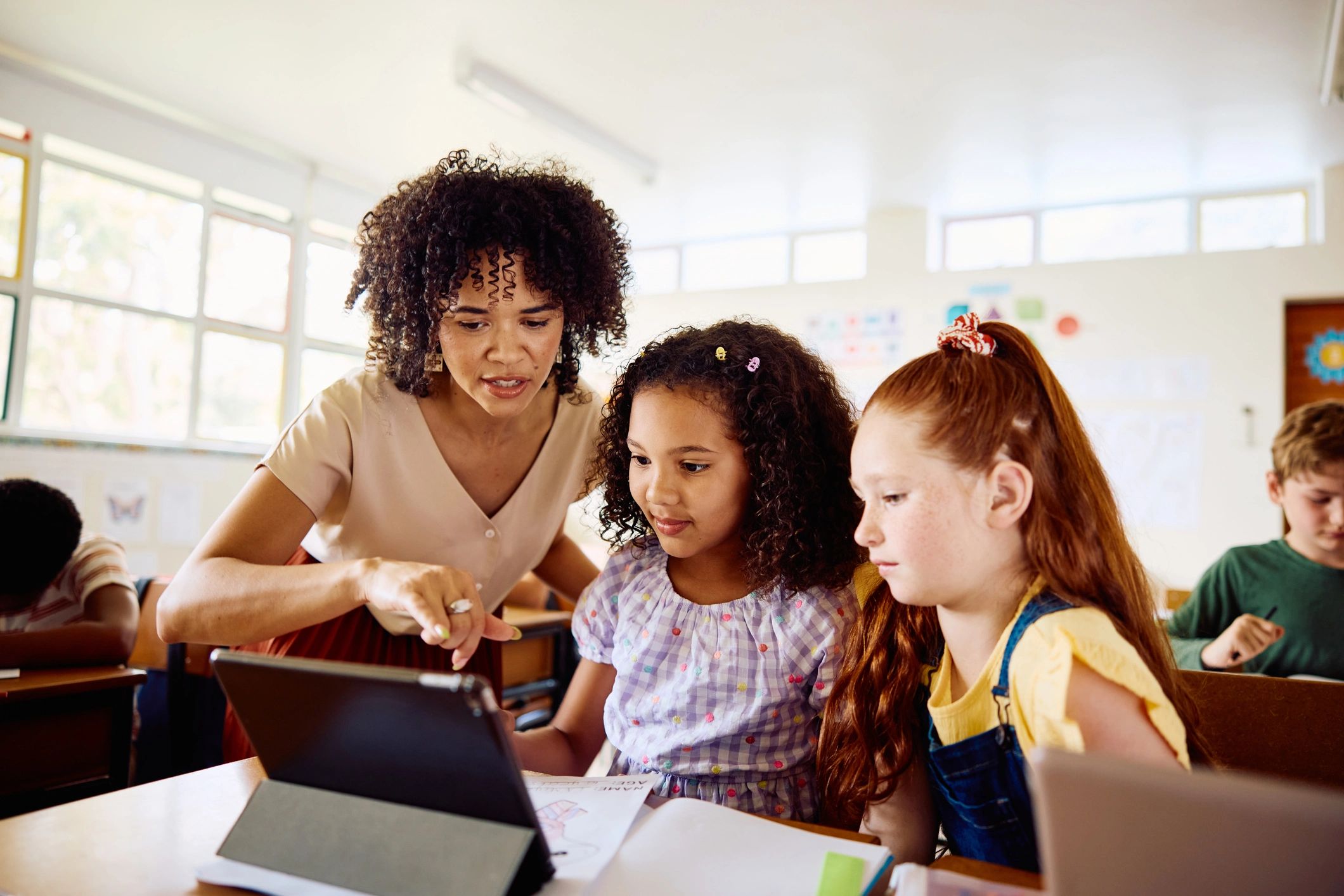 Teacher guiding students using a tablet in a classroom