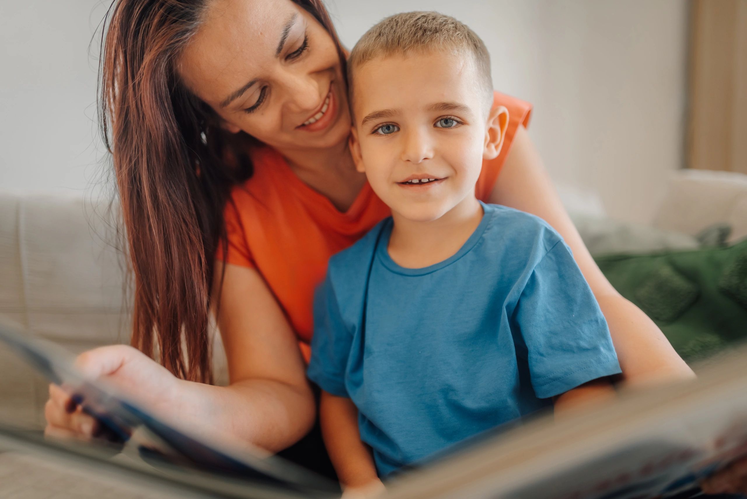 Parent reading a book with a child on a sofa